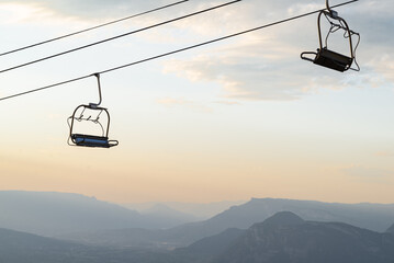 Chair lift with a background of mountain layers of french alps at sunset.