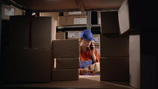 Customs warehouse worker. Woman with phone in warehouse calling to boss.