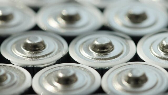 A lot of alkaline charged batteries with different polarity and power. Battery recycling, plus and minus, background. Rotation around its own axis. Macro