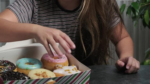 a girl chooses a donut from a box
