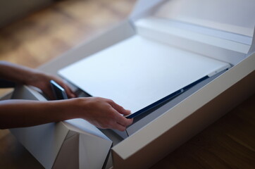 Tbilisi, Georgia - May 25, 2022: Woman removes white protective film from New iMac monitor. iMac Mi...