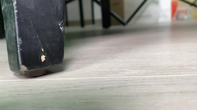 Old wooden scratched black colour couch leg moving into focus on ground floor close up view indoor with copy text space. Furniture and home renovate concept. 