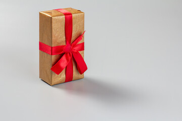 Gift box with a red ribbon on the gray background.