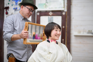 鏡でヘアスタイルを確認する美容師とお客 - obrazy, fototapety, plakaty