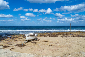 Qbajjar Bay, Gozo - October 13th 2020: A rowboat on a trailer on the beach in front of the sea.
