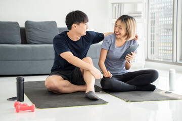 Couple resting after exercising at home Watch sports videos online Point to the screen Talk about exercise