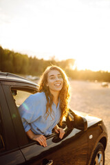 Smiling tourist leaning out of the car window enjoys the adventure, feels freedom, travels by car....
