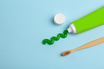 Tube of aloe toothpaste and toothbrush on light blue background, flat lay. Space for text