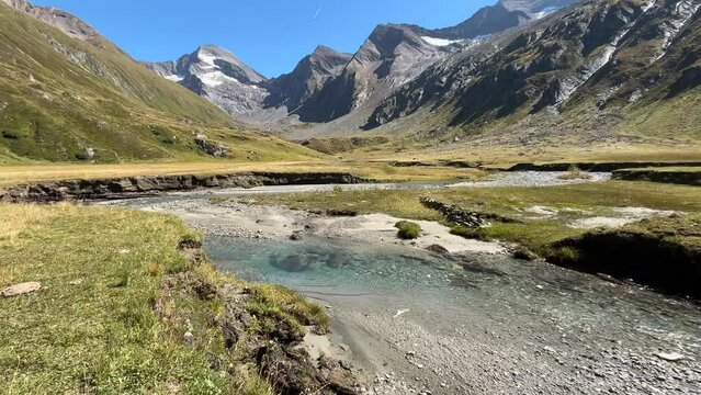 Panoramic view of Zillertal alps with clear stream in the summer season, Giogo Lungo hike in Valle Aurina, South Tyrol, Italy