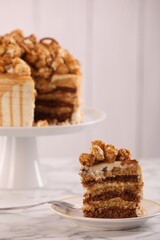 Piece of caramel drip cake decorated with popcorn and pretzels on white marble table