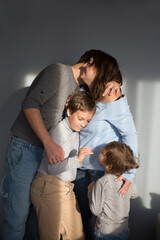 Fototapeta na wymiar family mom, dad and two children embrace against a grey background