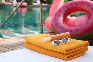 Beach accessories on sun lounger, inflatable ring and float near outdoor swimming pool. Luxury resort