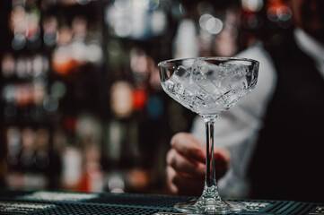 Ice cube in an empty glass on a bar counter in bar or pub