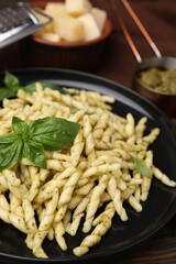 Plate of delicious trofie pasta with pesto sauce and basil leaves on table, closeup
