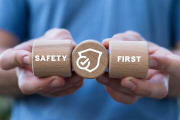Man holding wooden cylinders with inscription: SAFETY FIRST. Safety first, work safety, caution work hazards, danger surveillance, zero accident concept. Employees safety awareness at workplace.
