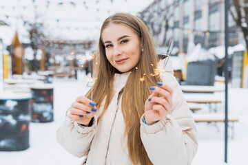 Caucasian young woman with blond hair lit sparklers on the street