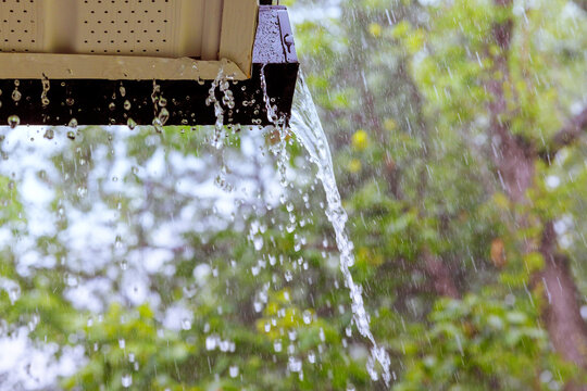 During heavy rain, water cascades from overflowing gutters.