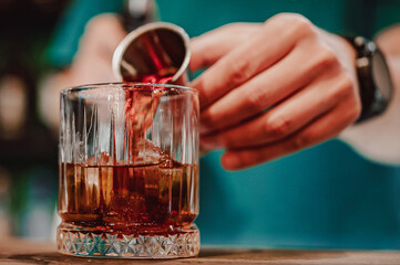 bartender hand making negroni cocktail in bar