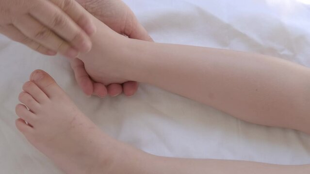close-up toddlers bare feet, female hands gently knead the child's legs, make therapeutic, preventive massage, strengthen musculoskeletal system, stimulate physical development, prevention of flat
