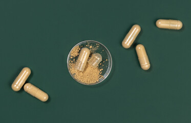 One capsule Opened in a jar on dark green. Taking dietary supplements with capsules