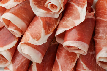 Rolled slices of delicious jamon as background, closeup