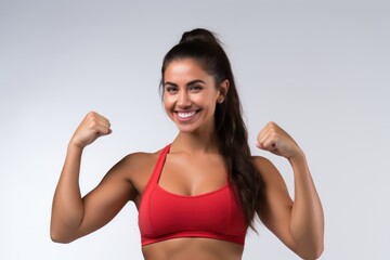Fototapeta na wymiar Portrait of a smiling sportswoman in red sportswear showing her biceps isolated on a white background and Looking at the camera.