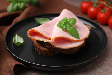Delicious sandwich with ham on brown table, closeup