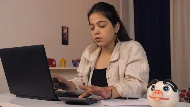 A Pretty Indian Woman Sitting At A Desk - Accounting Job  Data Entry  Accountant  Work At Home  Late Night Assignment . Working Indian Woman Using Calculator And Doing Entries On Laptop - Budget Pr...