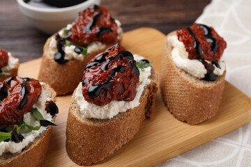 Delicious bruschettas with sun-dried tomatoes, cream cheese and balsamic vinegar on table, closeup