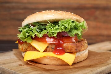 Delicious burger with tofu, fresh vegetables and sauce on wooden board, closeup