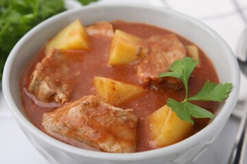 Delicious goulash with parsley in bowl, closeup