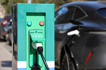 Fototapeta premium Electric car charging, eco-friendly transport. Charging station on a city street