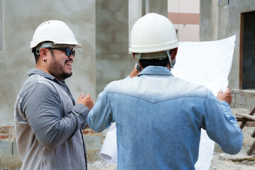 Engineer builder, standing together discussing plans, concerning construction row house with many...