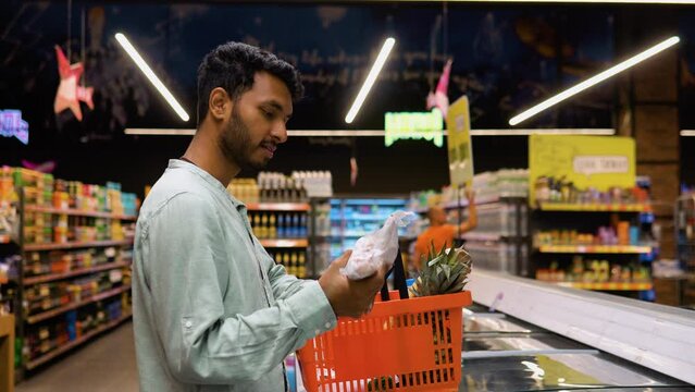 Indian man shopping for frozen fish seafood in supermarket retail store