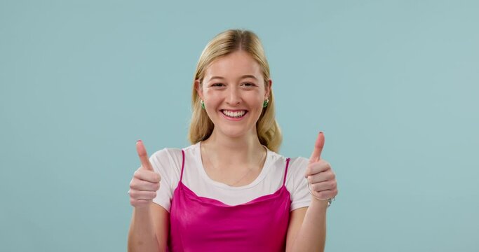 Happy, thumbs up and face of woman on blue background for good news, agreement and approval. Success, emoji and portrait of person with hand gesture for achievement, yes sign and winning in studio