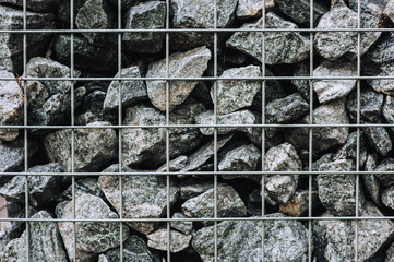 A lot of decorative stones, cobblestones in a metal lattice, cage. Close-up photography, decor.