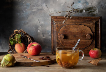 Compote of apples and raisins in a transparent glass mug on a wooden table