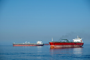 Fototapeta na wymiar Container cargo ship loaded leaves Piraeus port Greece. Smoke from ship chimney, moored vessel, sea.