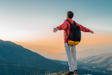 A happy man hiker standing with hands open on the mountain top adventure travel concept of free...