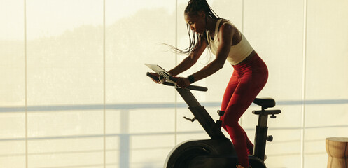 Fit and healthy: Young woman exercising on smart stationary bike