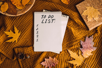 Autumn To Do List in open notepad with fall leaves at home. Fall Bucket List Autumn Activities and Fun Things to Do.