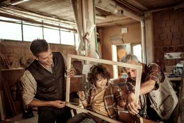Multigenerational family including a son , father and grandfather working with wood in a carpentry workshop