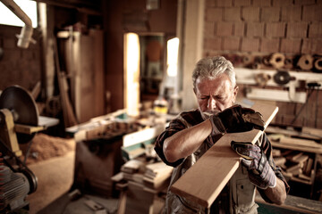 Senior Caucasian male carpenter working with wood in a carpentry workshop