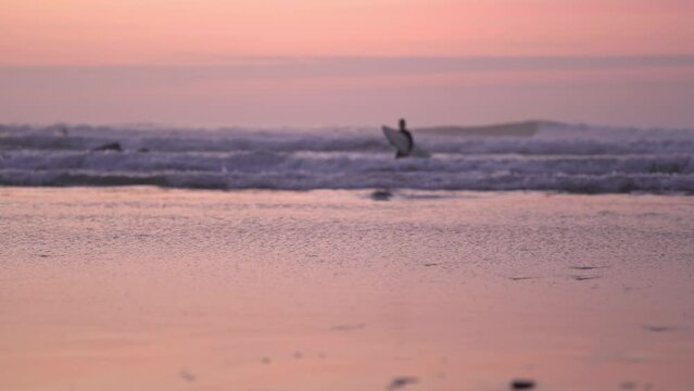 deporte acuático surfista saliendo del agua tonos rosas del anochecer