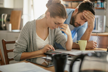 Worried young Caucasian couple going over their bills and home finances in the morning in the...