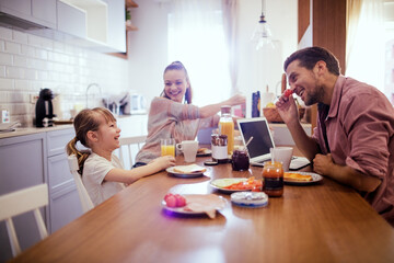Happy Young Caucasian family having breakfast together in the kitchen in the morning