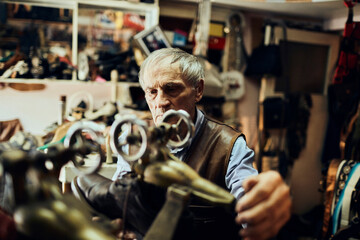 Senior male shoemaker restoring a shoe in his old workshop in the city