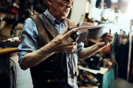 Senior male cobbler restoring a shoe in his old workshop in the city