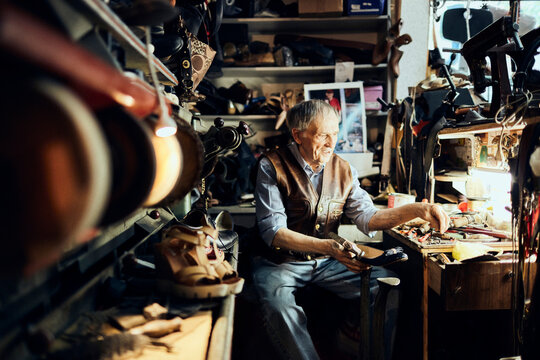 Senior male shoemaker restoring a shoe in his old workshop in the city
