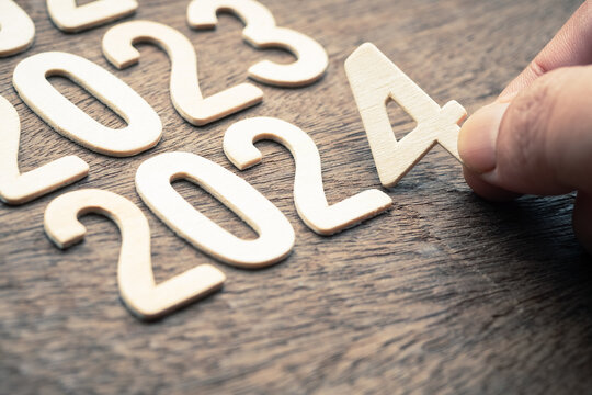 Closeup hand arranges the wooden numbers in order from 2023 to 2024, new year plan in focus